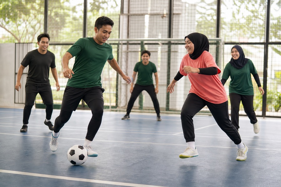 Friends playing a casual futsal match on an indoor community court